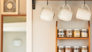 A kitchen shelf with jars labeled with spices like Mexican Seasoning, Paprika, Turmeric, Garlic, Chili, Cinnamon, Rosemary, and Curry Powder. - The Secret Studio, Outdoor Bath & Pizza Oven (New Plymouth)