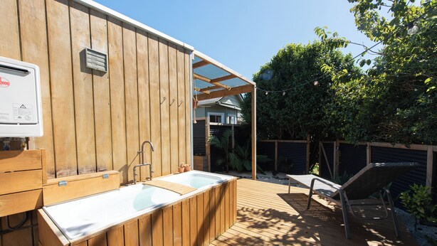 A wooden deck with a hot tub and a chair. - The Secret Studio, Outdoor Bath & Pizza Oven (New Plymouth)