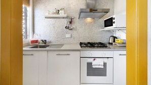 A kitchen with a marble backsplash, stainless steel appliances, and a window with blinds. - Holiday Apartment 'Riva Mare 2' Near the Beach with Sea View and Parking Space (Vado Ligure)