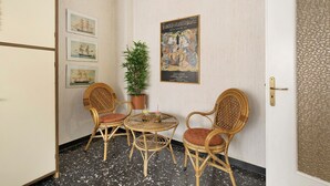 A room with a round table, two wicker chairs, a potted plant, and a poster on the wall. - Holiday Apartment 'Riva Mare 2' Near the Beach with Sea View and Parking Space (Vado Ligure)