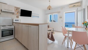 Una cocina moderna con estufa, microondas y armarios, que da paso a un comedor con mesa y sillas.