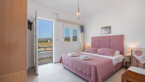 Un dormitorio con cama, mesita de noche, silla, ventana y puerta que da a un espacio exterior.