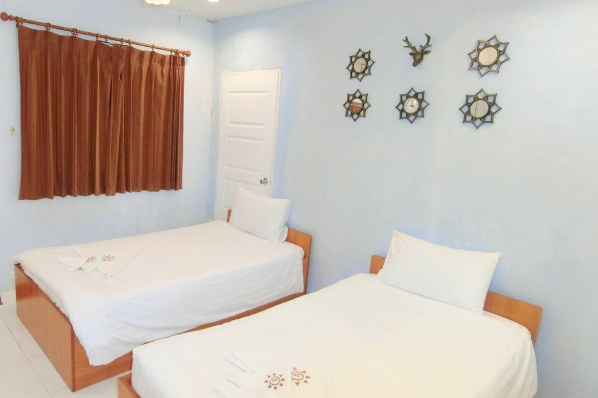 Ein Schlafzimmer mit zwei Betten, einem braunen Vorhang, einer weißen Tür und vier Wanduhren.