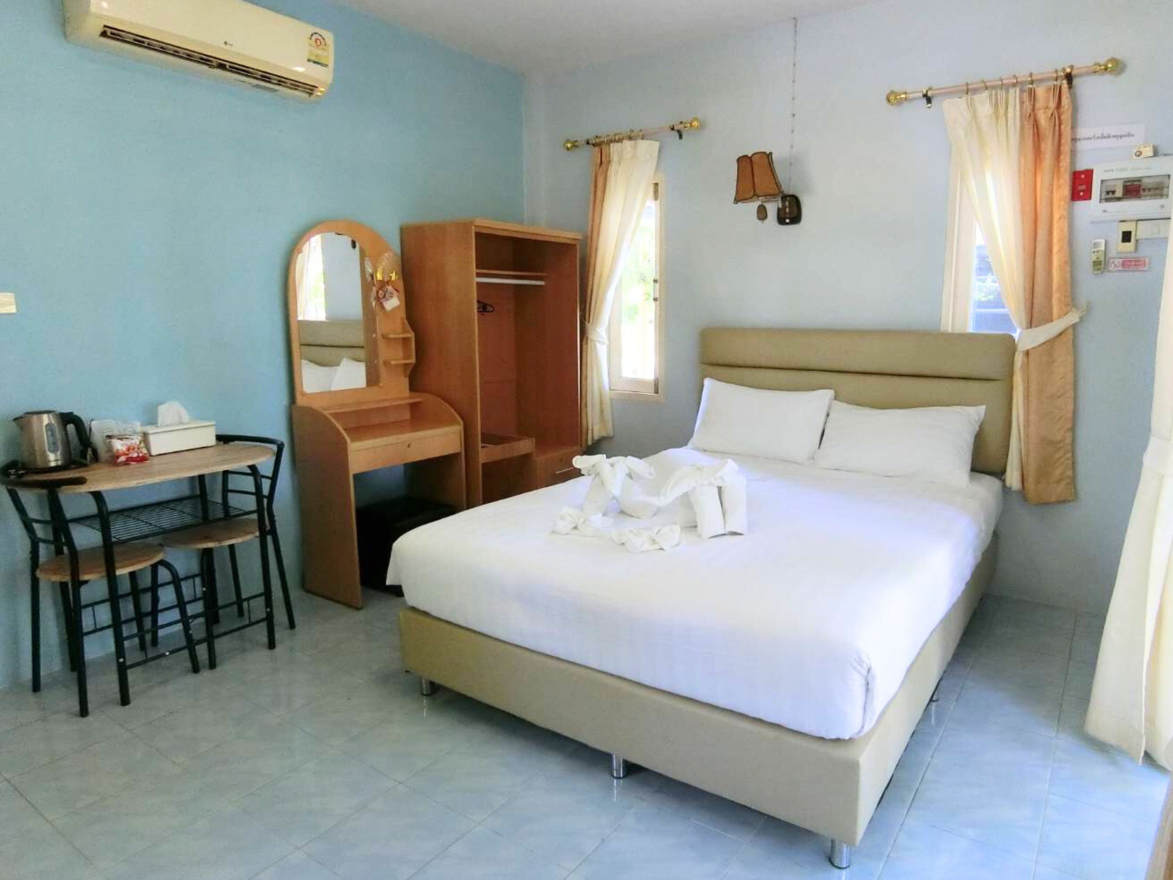 Una habitación de hotel con cama, escritorio con silla, espejo, armario y aire acondicionado.