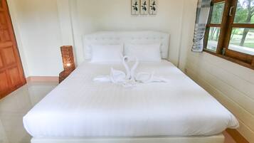 A neatly made bed with white linens and a swan-shaped towel arrangement.