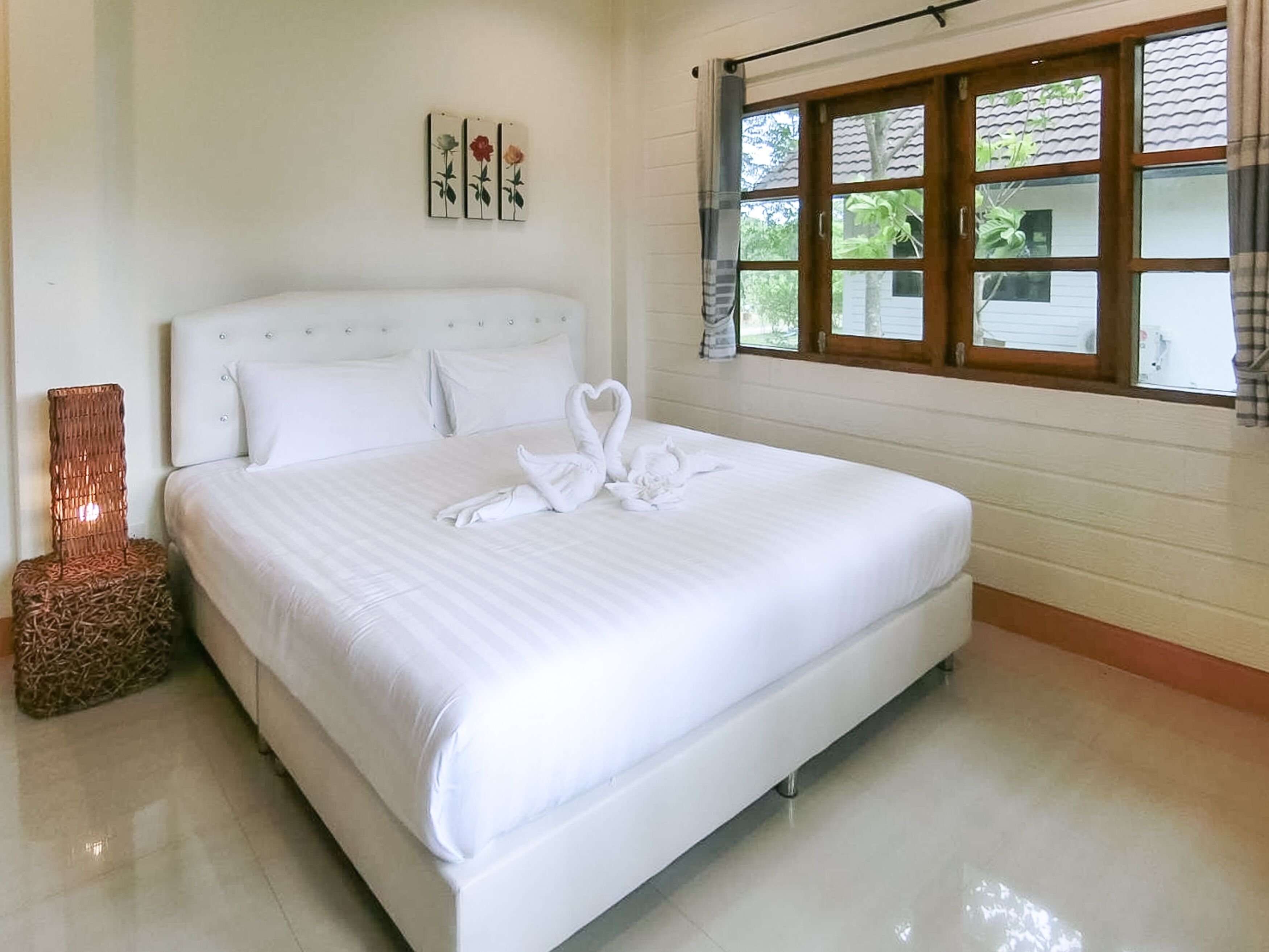 A neatly made bed with white linens and two swan-shaped towels.