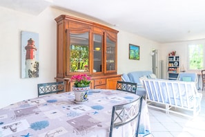 A dining area with a table set for two, a cabinet with glass doors, and a crib in the background.