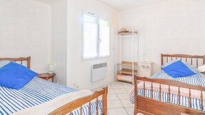 Een kamer met twee houten bedden, een witte radiator, een raam en een witte kast.