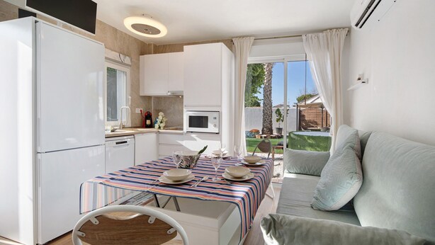 A compact kitchen with a refrigerator, microwave, and dining area with a table set for two.