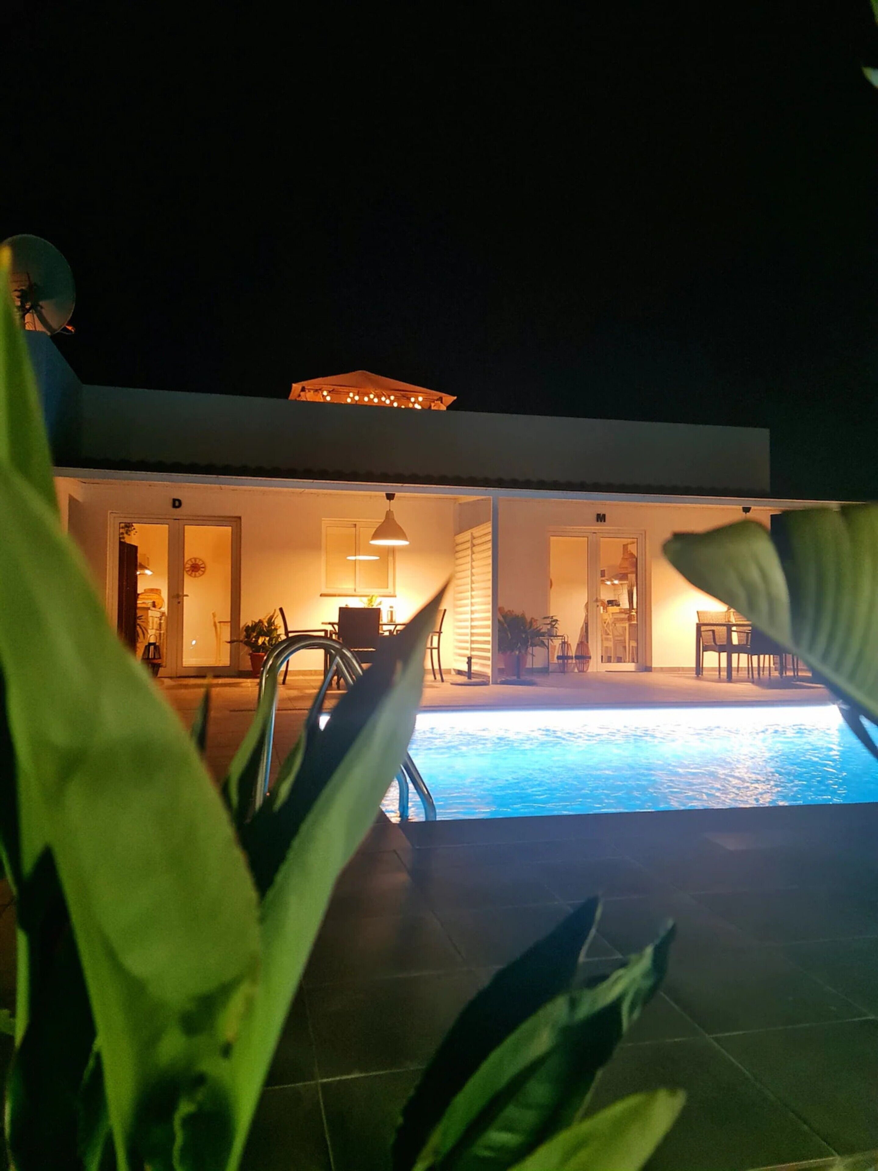 A modern house with a swimming pool, outdoor furniture, and a covered patio area.