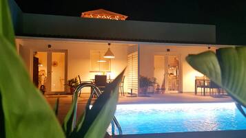 A modern house with a swimming pool, outdoor furniture, and a covered patio area.