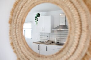 Une cuisine avec des meubles blancs, un évier en acier inoxydable et une plante suspendue.
