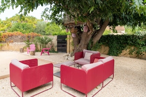 A patio with red furniture, a tree, and a fence.