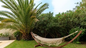 Eine Hängematte in einem Garten mit einer Palme und üppigem Grün.