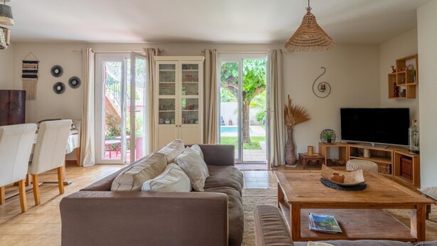 Ein Wohnzimmer mit Sofa, Couchtisch, Fernseher und Blick ins Freie.