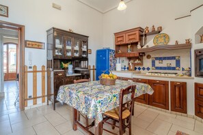 Une cuisine avec une table à manger, des meubles de rangement en bois, un réfrigérateur bleu et un dosseret carrelé.