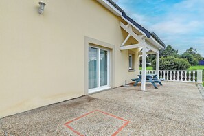 A building with a covered patio area, a white fence, and a table.
