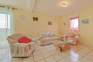 A living room with two sofas, a coffee table, a clock, and a window with curtains.