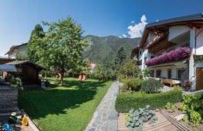 Um hotel com caminho de pedra, vegetação exuberante e vista para as montanhas.