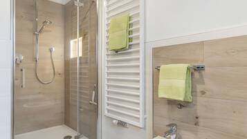 Un baño moderno con ducha envuelta en vidrio, un bidé y paneles de pared de madera.