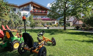 A lawn mower and a riding lawn mower in a grassy yard with a house in the background.