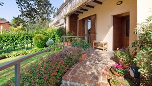 A building with a stone patio, wooden shutters, and potted plants.