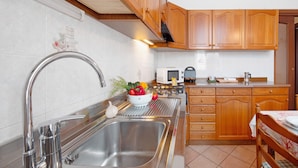A kitchen with wooden cabinets, a stainless steel sink, a microwave, and a gas stove.