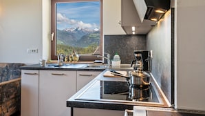A kitchen with a view of mountains, a coffee maker, and a sink.