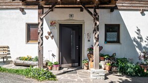 A traditional building with a wooden porch, a door marked with the number 9, and various potted plants around the entrance.