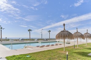 A swimming pool with a tiled deck, palm trees, and a view of the ocean. - Apartment 'Atico Antonio Sol' with Sea View, Wi-Fi and Air Conditioning (Torrox)