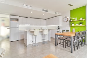 Une cuisine moderne avec des meubles blancs, une table à manger en bois et des tabourets de bar.