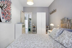 A bedroom with a bed, a dresser, a mirror, and a nightstand with a lamp. - Vacation Home "Casa Leon" with Sea View, Balcony & Wi-Fi (Corralejo)