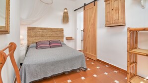 Un dormitorio con cama, armario de madera y una silla.