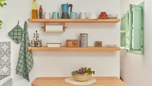 Una cocina con estantes de madera, un cuenco de fruta y una cafetera.