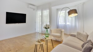 A modern living room with a flat-screen TV, a sofa, a coffee table, and a lamp. - Apartment 'My Holidays Home' with Balcony, Wi-Fi and Air Conditioning (Palamós)
