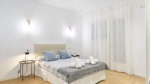 A hotel room with a bed, bedside tables, and a curtain. - Apartment 'My Holidays Home' with Balcony, Wi-Fi and Air Conditioning (Palamós)