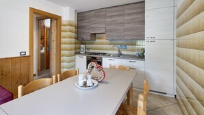 Eine moderne Küche mit Holzausstattung, einem Esstisch mit Stühlen und einem dekorativen Kranz.