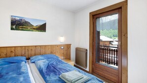 Ein Schlafzimmer mit zwei Betten, einem Holz-Kopfstück, einem Heizkörper und einem Fenster mit Bergblick.