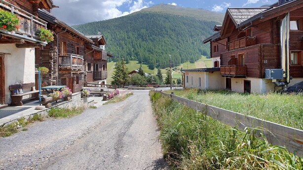 Ein rustikales Holzhaus mit Balkonen, einem Kiesweg und einem Berg im Hintergrund.