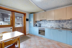 Eine Küche mit hellblauen Schränken, einer Mikrowelle, einem Backofen, einer Spüle und einem Esstisch mit Stühlen.