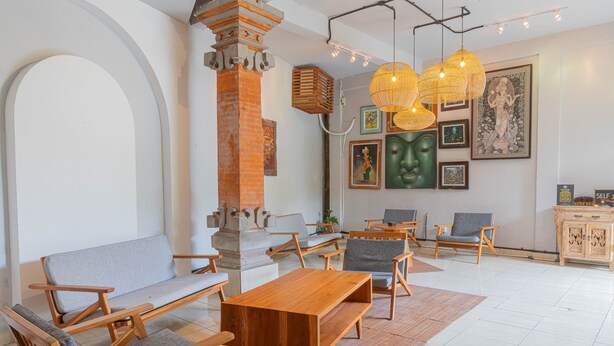 A modern living room with wooden furniture, a stone pillar, and artwork on the walls. - Nobody Inn Bali (Ubud)