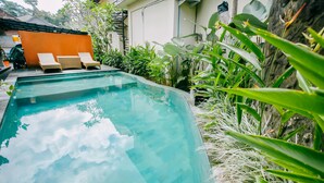 A swimming pool with lounge chairs and tropical plants. - Nobody Inn Bali (Ubud)