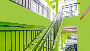 Un intérieur à plusieurs niveaux, avec des murs d’un vert vif et des rampes en métal.