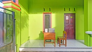 Une pièce avec un mur vert, un bureau en bois avec un ordinateur portable, une chaise et une porte portant un numéro.