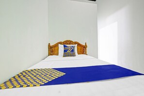 A bed with a wooden headboard, white bedding, and a blue and yellow patterned throw. - OYO 90760 Almadina Family Homestay (Jepara)
