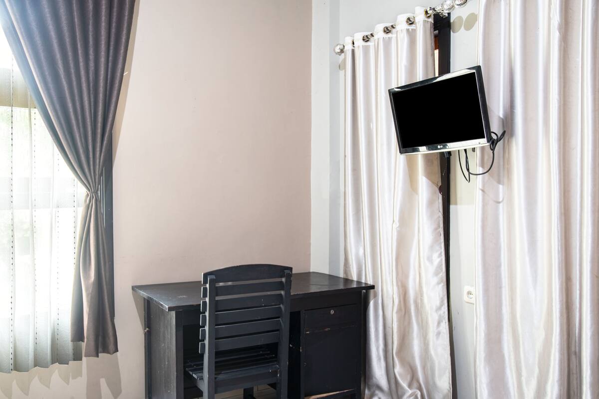 A room with a desk, chair, and a mounted TV.