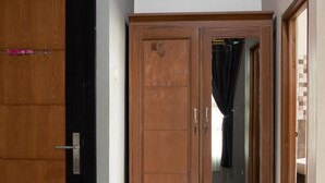 A hallway with a wooden wardrobe, a mirrored wardrobe, and a tiled floor.