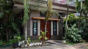 A modern house with a well-maintained garden, including various potted plants and a palm tree.