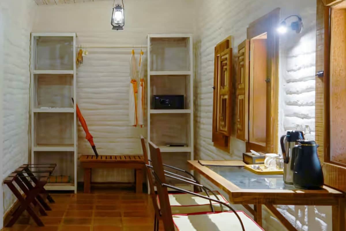 A room with a wooden chair, a small table, and a shelf unit with various items.