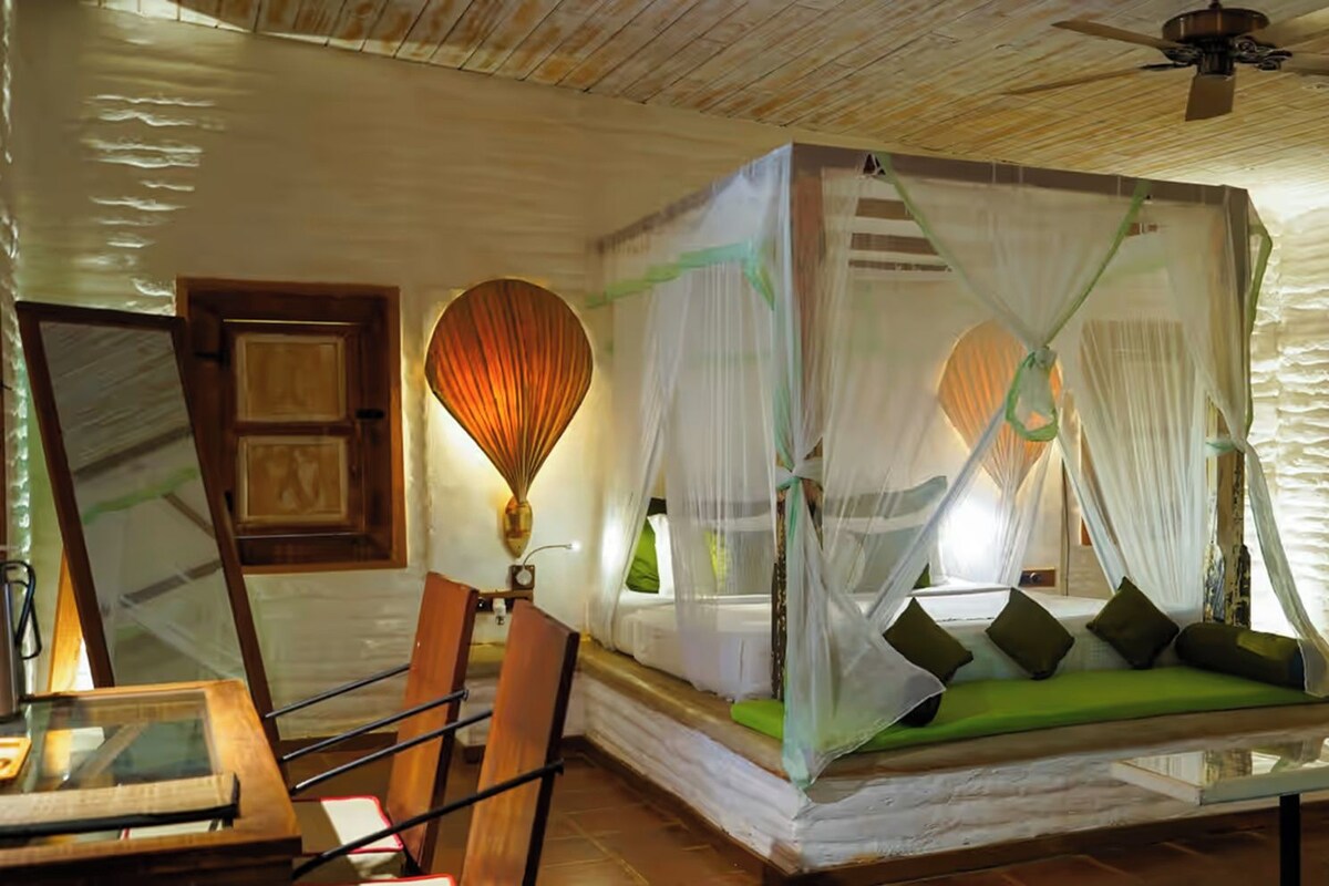 A room with a canopy bed, a ceiling fan, and a rustic wooden floor.